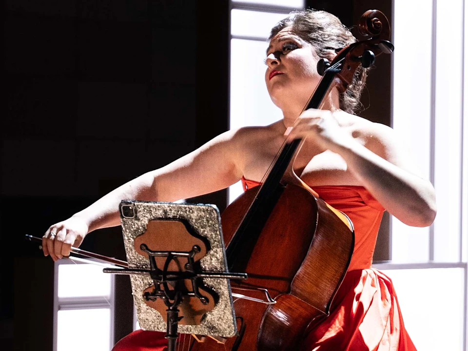 A woman in a red dress playing the cello.