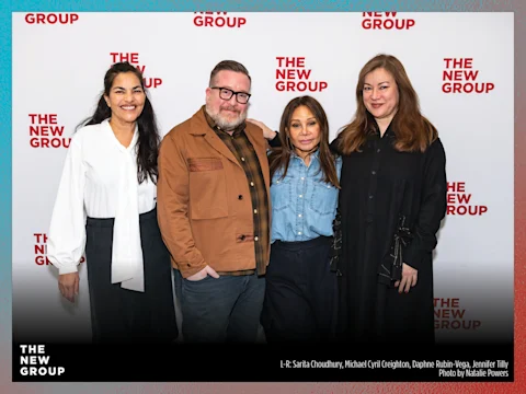 Four people stand side by side, smiling, in front of a backdrop with "The New Group" logo.