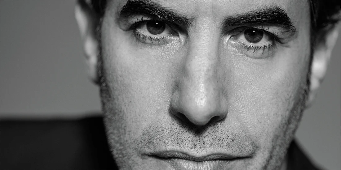 Black and white close-up portrait of Sacha Baron Cohen.