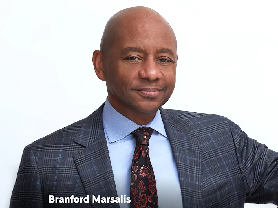 Headshot of Branford Marsalis wearing a suit and patterned tie.