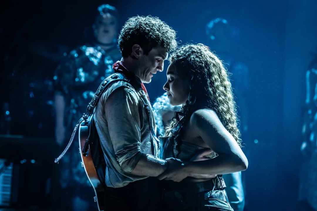 Production image of Hadestown in London, featuring Dónal Finn as Orpheus and Grace Hodgett Young as Eurydice.