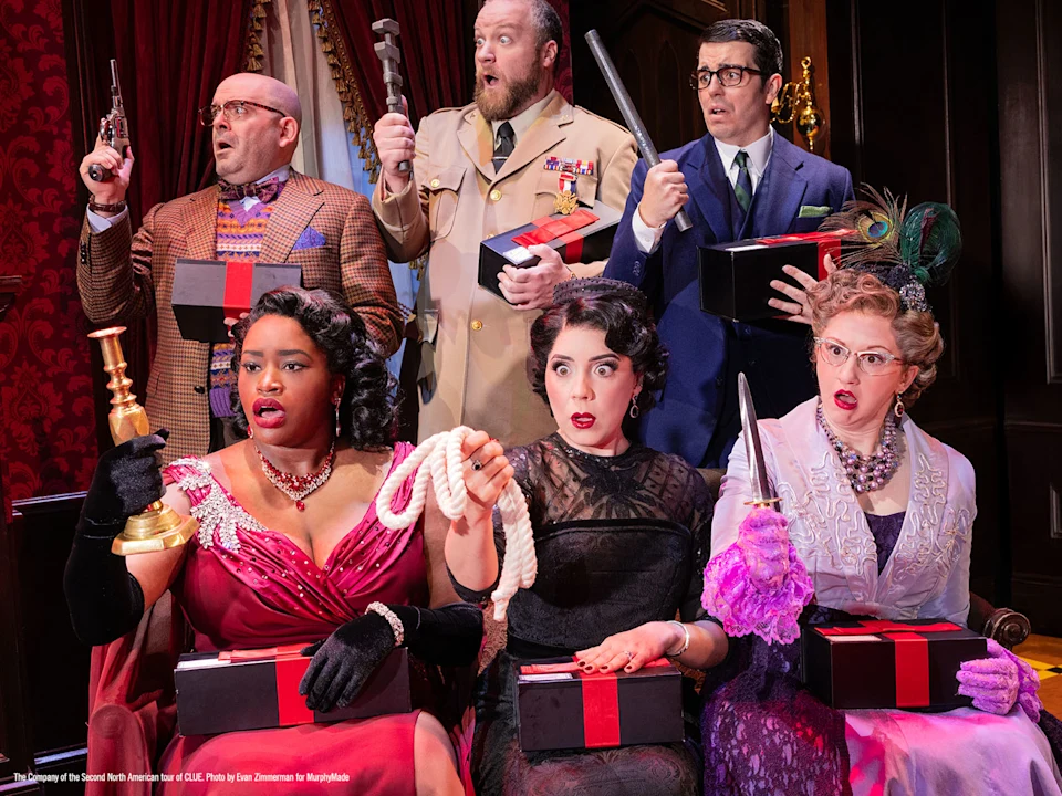 Six people in vintage formal attire hold weapons and black gift boxes, displaying shocked or surprised expressions in an ornately decorated room.