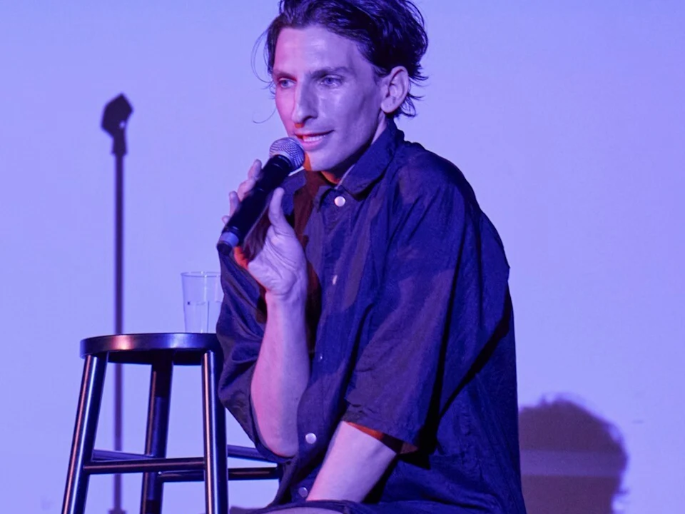 Photo of Morgan Bassichis seated on a stool on stage in Can I Be Frank?