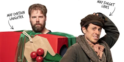 A man in a red gift-wrapped box labeled “May contain laughter” stands next to a man in a flat cap and scarf labeled “May forget lines.”