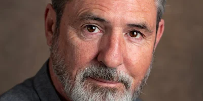 Headshot of a middle-aged man with gray hair and a beard looking directly at the camera.