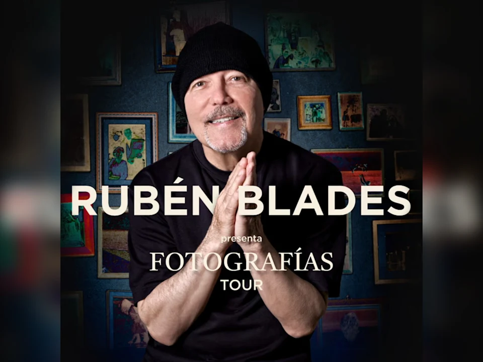 Rubén Blades smiles and clasps his hands in front of a wall with framed photos; text reads "Rubén Blades presenta Fotografías Tour.