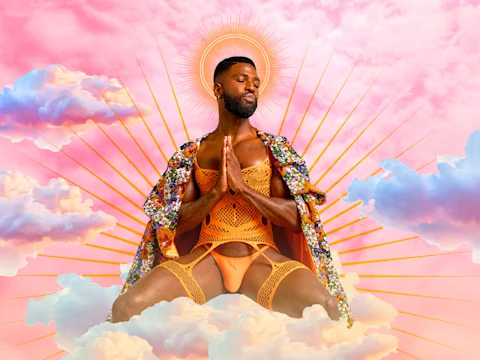 A person in orange lingerie and a floral robe sits on clouds with hands in prayer, surrounded by radiant sun rays and a pink sky background.