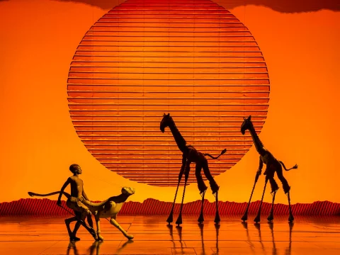 Production shot of The Lion King in London, showing cheetah and giraffes.
