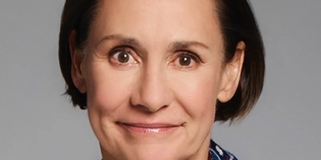 A middle-aged woman with short brown hair smiles softly at the camera against a plain background.
