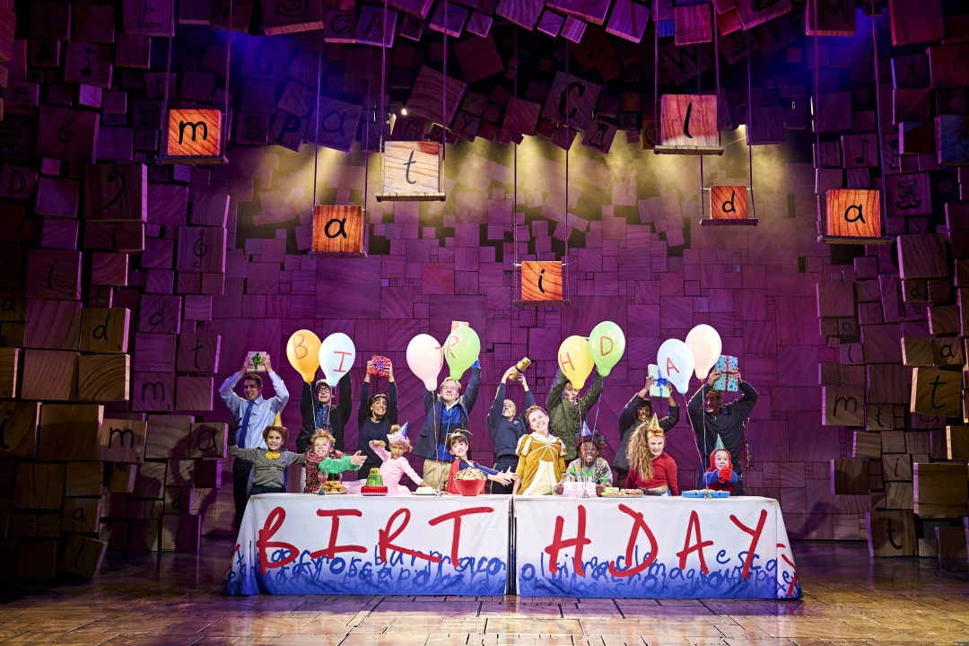 Production shot of Matilda The Musical in London, showing Matilda's birthday celebration.