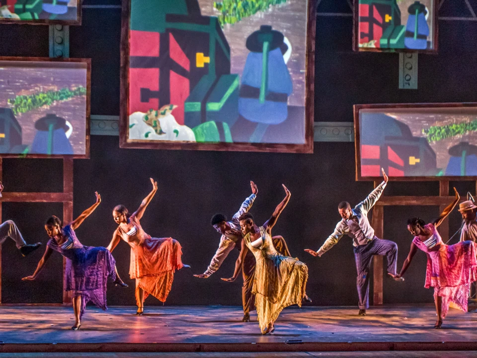 Production photo of The Migration: Reflections on Jacob Lawrence in Washington with a group of dancers perform energetically on stage.