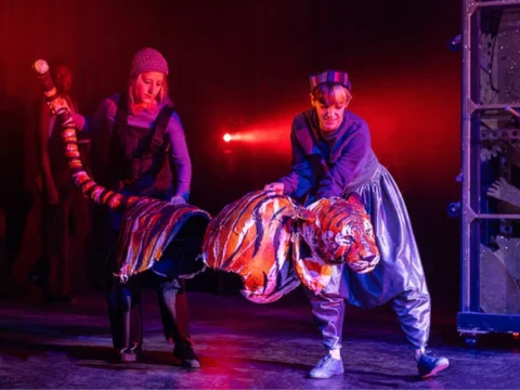 Two people carrying a prop tiger