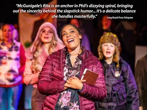 A woman in a plaid shirt and jacket holds a notebook on stage. Other performers are in the background, with a review quote above them.