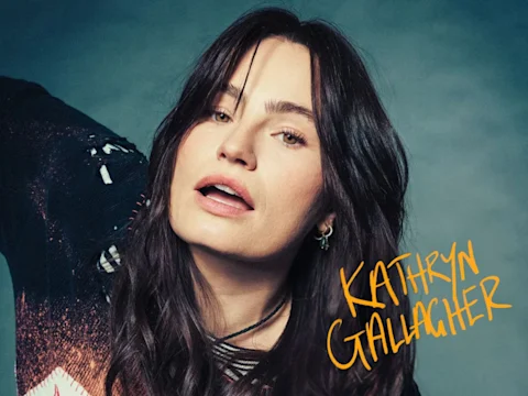 A person with long dark hair poses against a neutral background. The name "Kathryn Gallagher" is written in the bottom right corner.