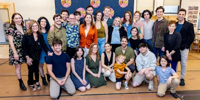 A group of adults and children pose together indoors, smiling at the camera in front of a colorful “Back to the Future” backdrop.