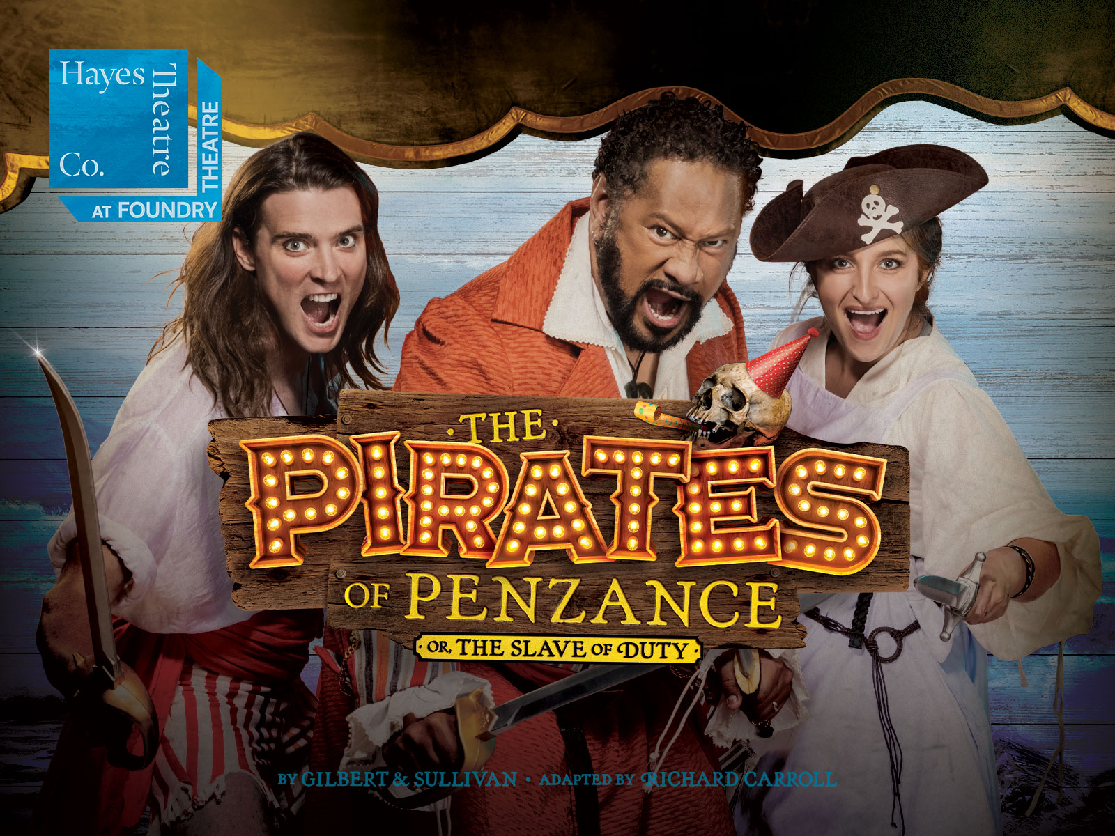 Three actors in pirate costumes pose enthusiastically in front of a wooden backdrop with a sign that reads "The Pirates of Penzance" at Hayes Theatre Co.