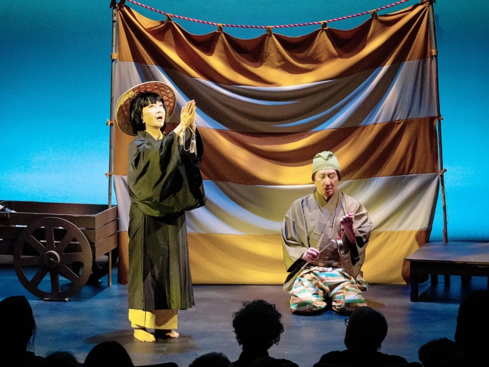 Two performers in traditional Japanese attire are on stage. 