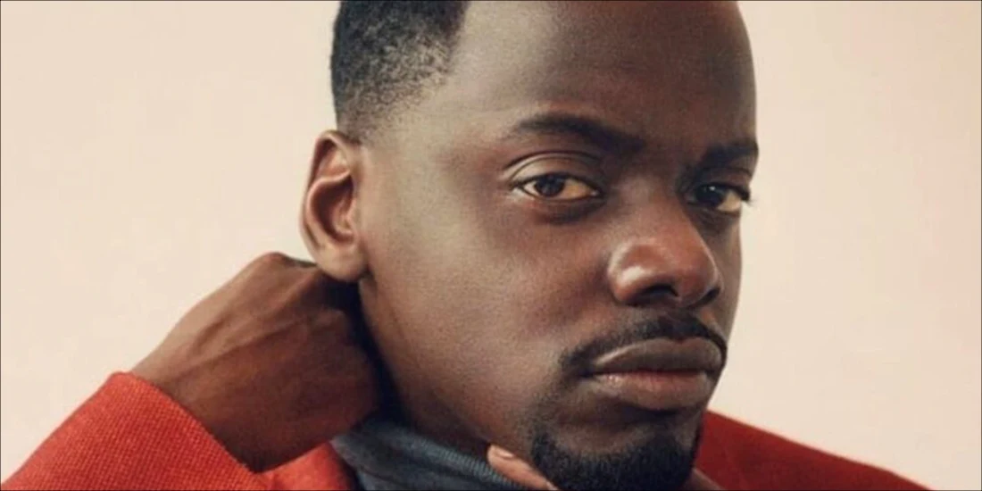 Close-up portrait of actor Daniel Kaluuya looking at the camera with one hand near his chin.