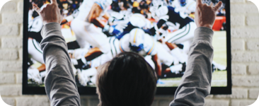 Person facing a television cheering at an American football game.
