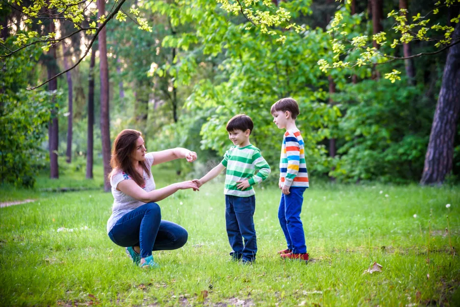 A mother applies tick repellent on her sons