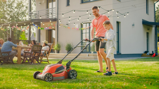 Parent with a child mowing the lawn