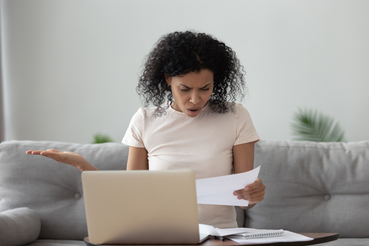Woman looking frustrated and upset while dealing with paperwork.