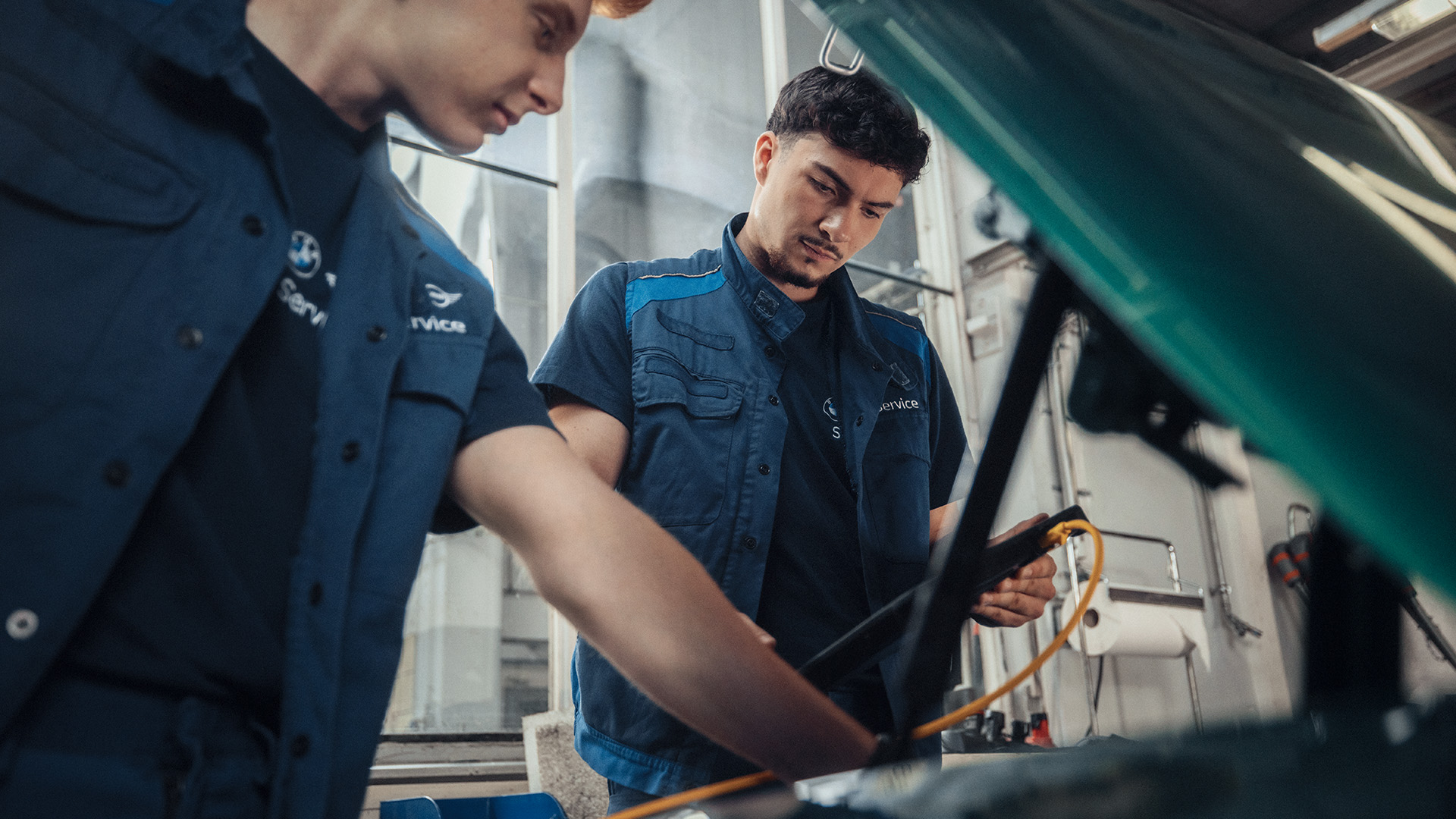 Two mechanics inspecting a car