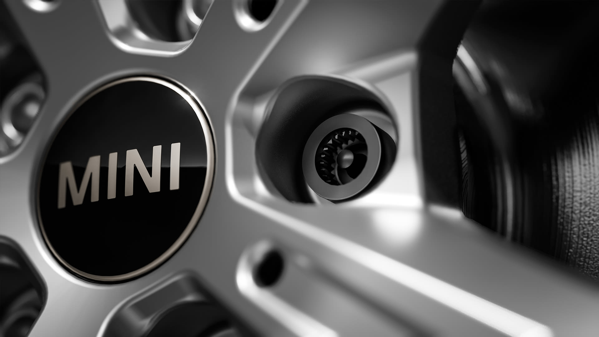 Close-up of a MINI car wheel showing the central hub with the MINI logo and a detailed view of one of the MINI wheel bolts.