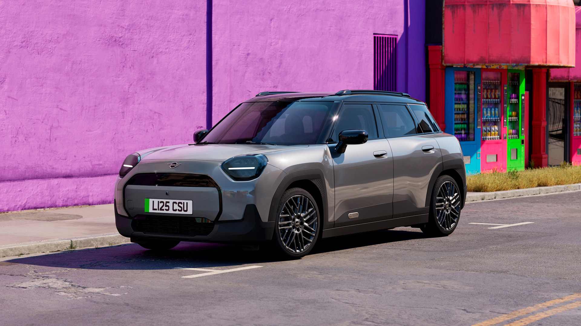 Gray MINI Aceman parked on a street in front of a building with a vibrant purple wall.