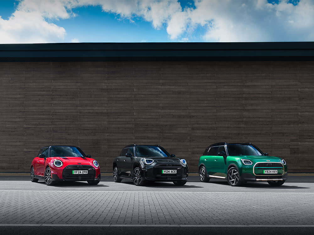 Three MINI cars parked side by side in front of a modern building.