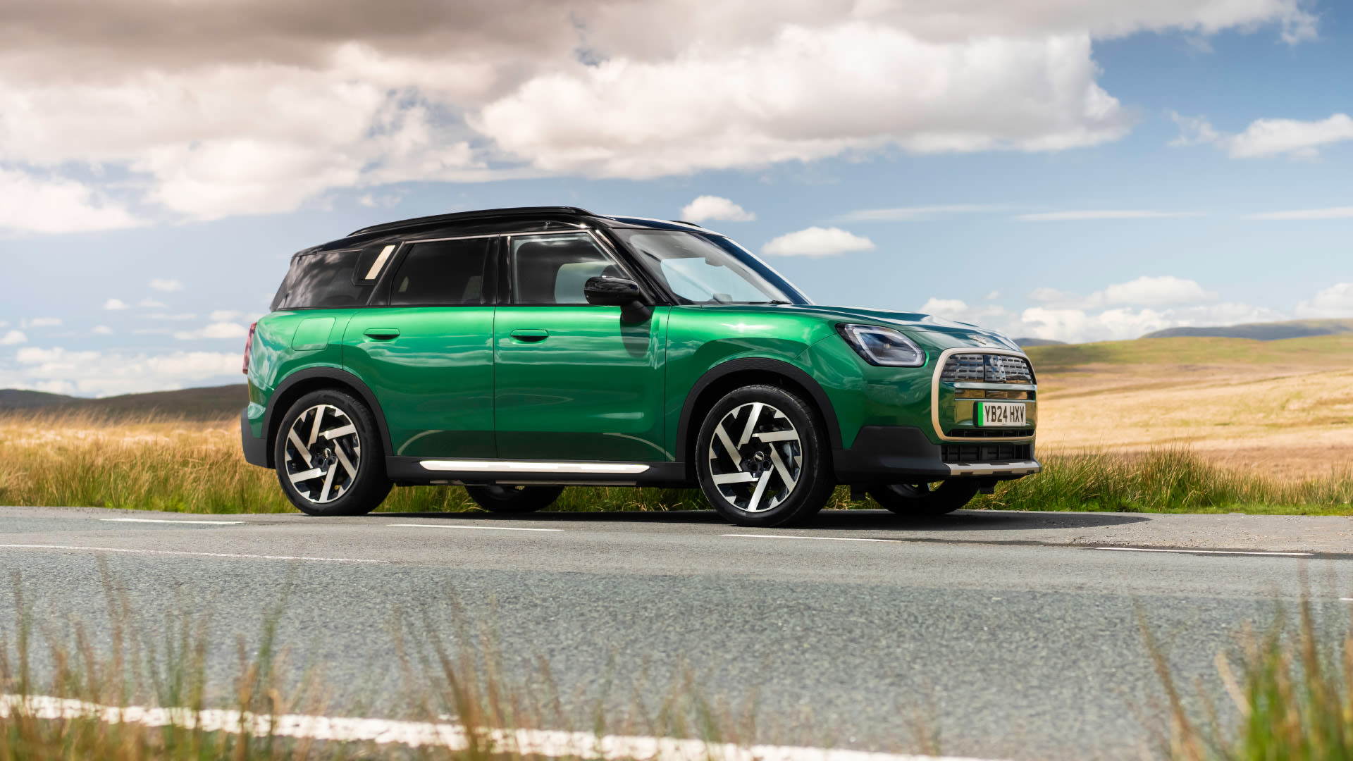 Side view of a green MINI Countryman Electric in a rural setting.