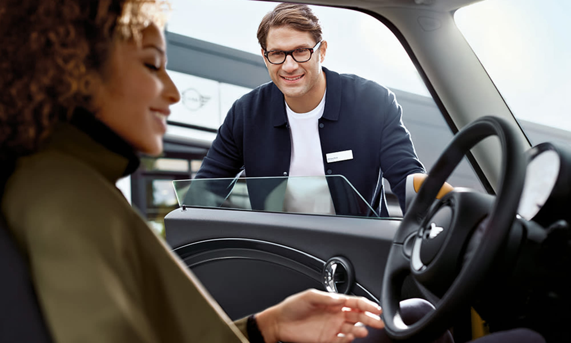 Customer seated inside a MINI while a centre representative explains the car’s features.