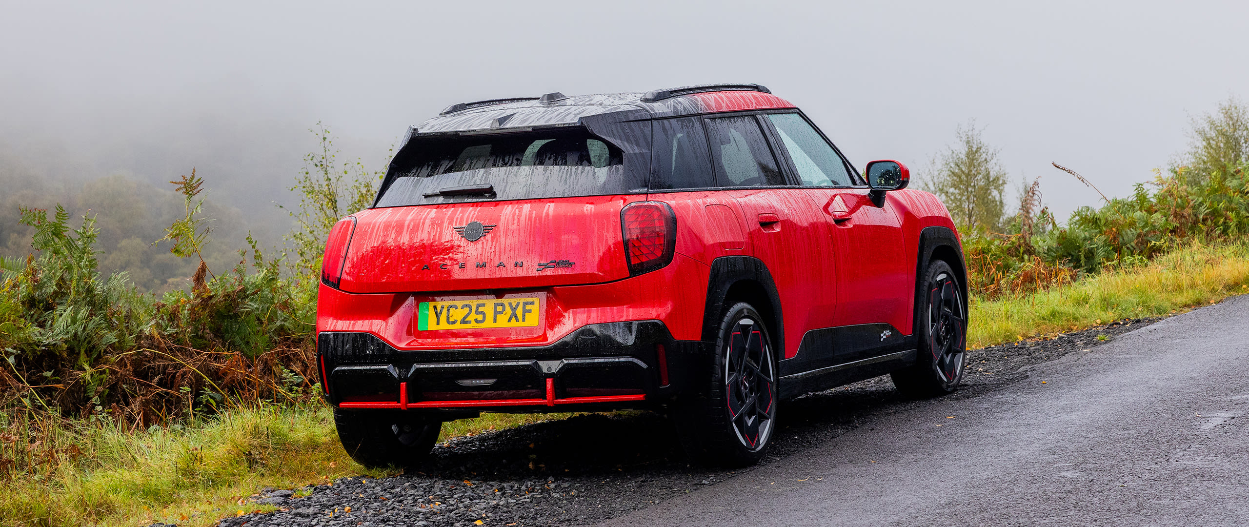 An red MINI Aceman parked on the side of a country road.