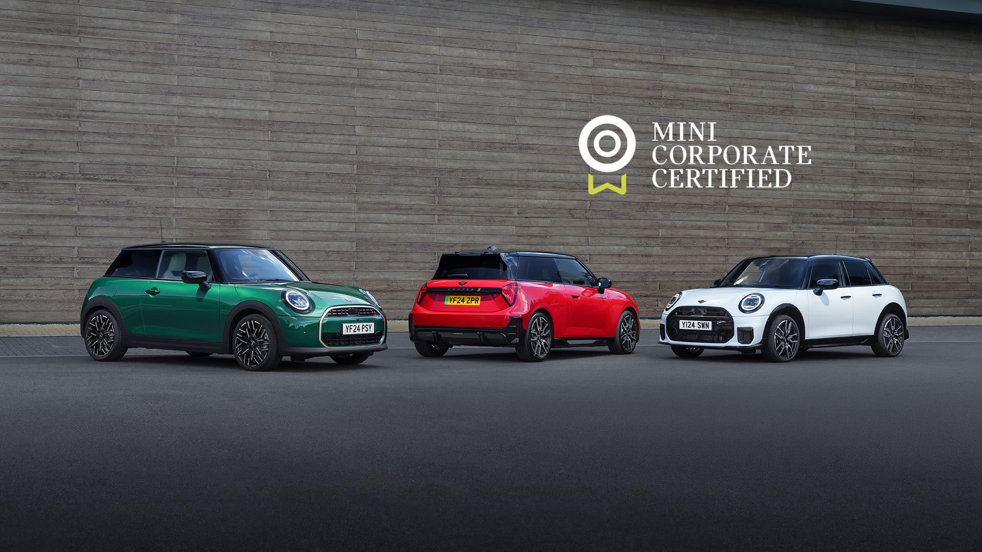 Three Mini Cooper cars—green, red, and white—parked side by side in front of a wooden wall with the text 'MINI CORPORATE CERTIFIED' and a circular logo below them.