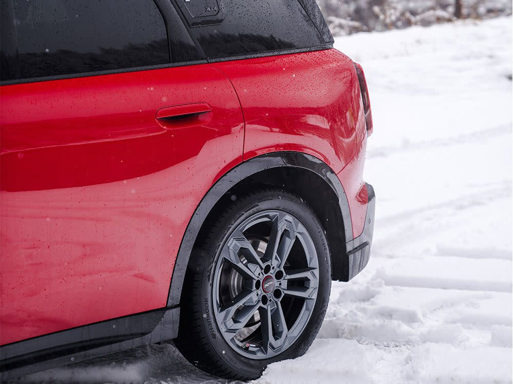 Rear side view of a red MINI Countryman parked in a snowy landscape.