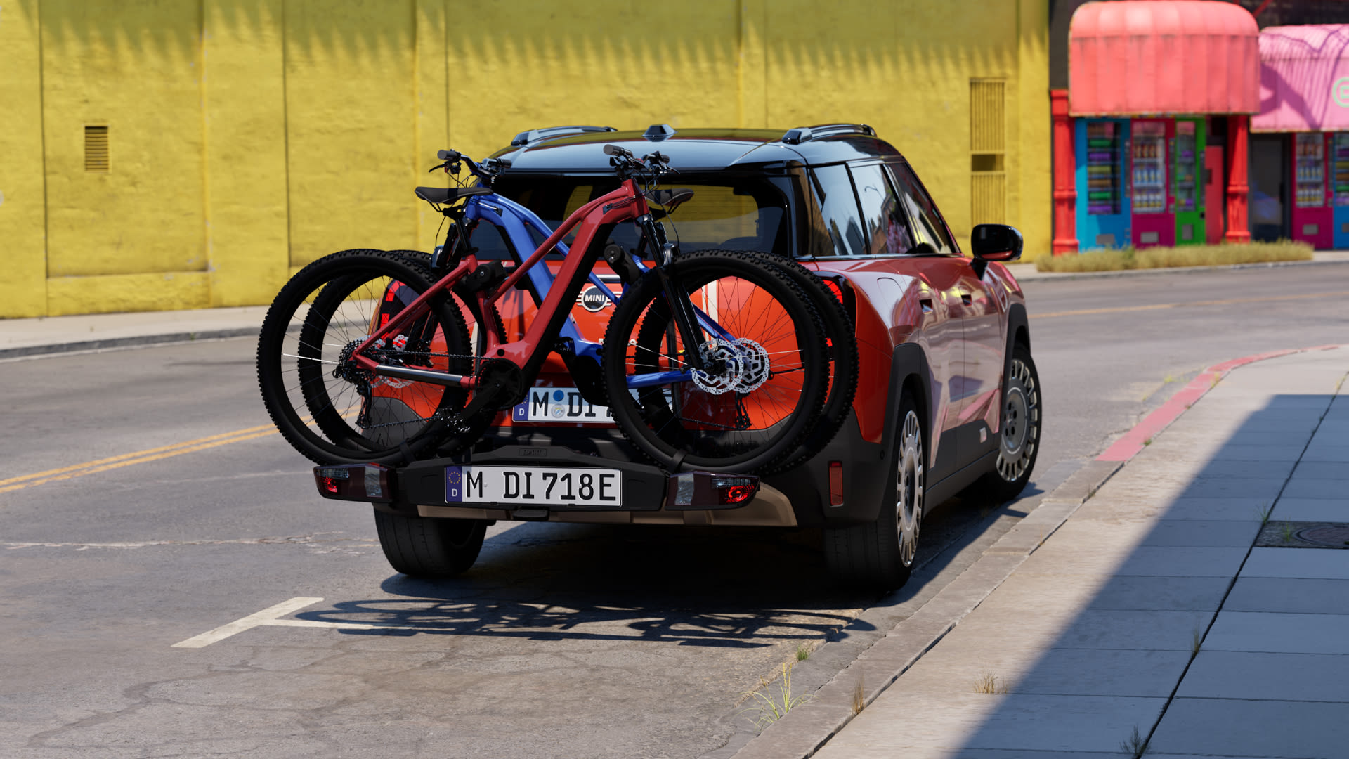 White MINI Countryman driving through a city street with two bicycles mounted on a rear rack.