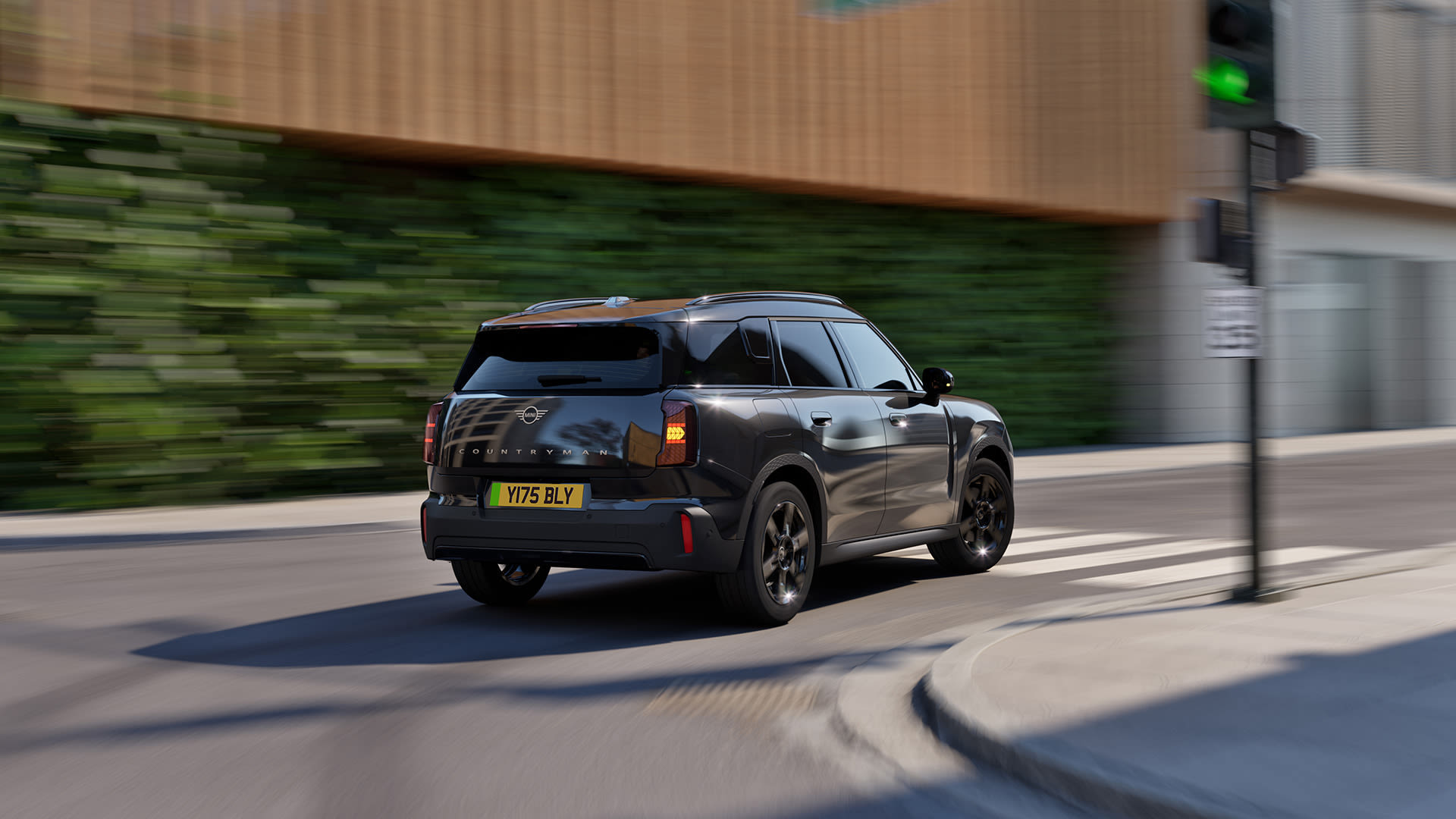 Black MINI model driving down on road by a building