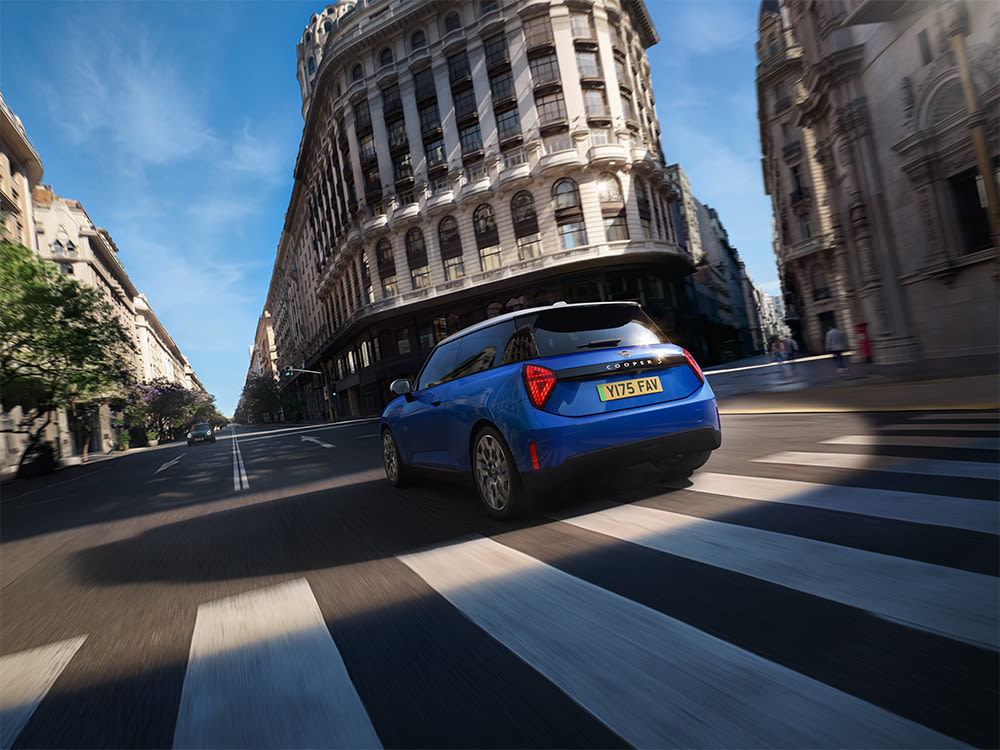 Rear view of a blue MINI Cooper electric driving through a city.