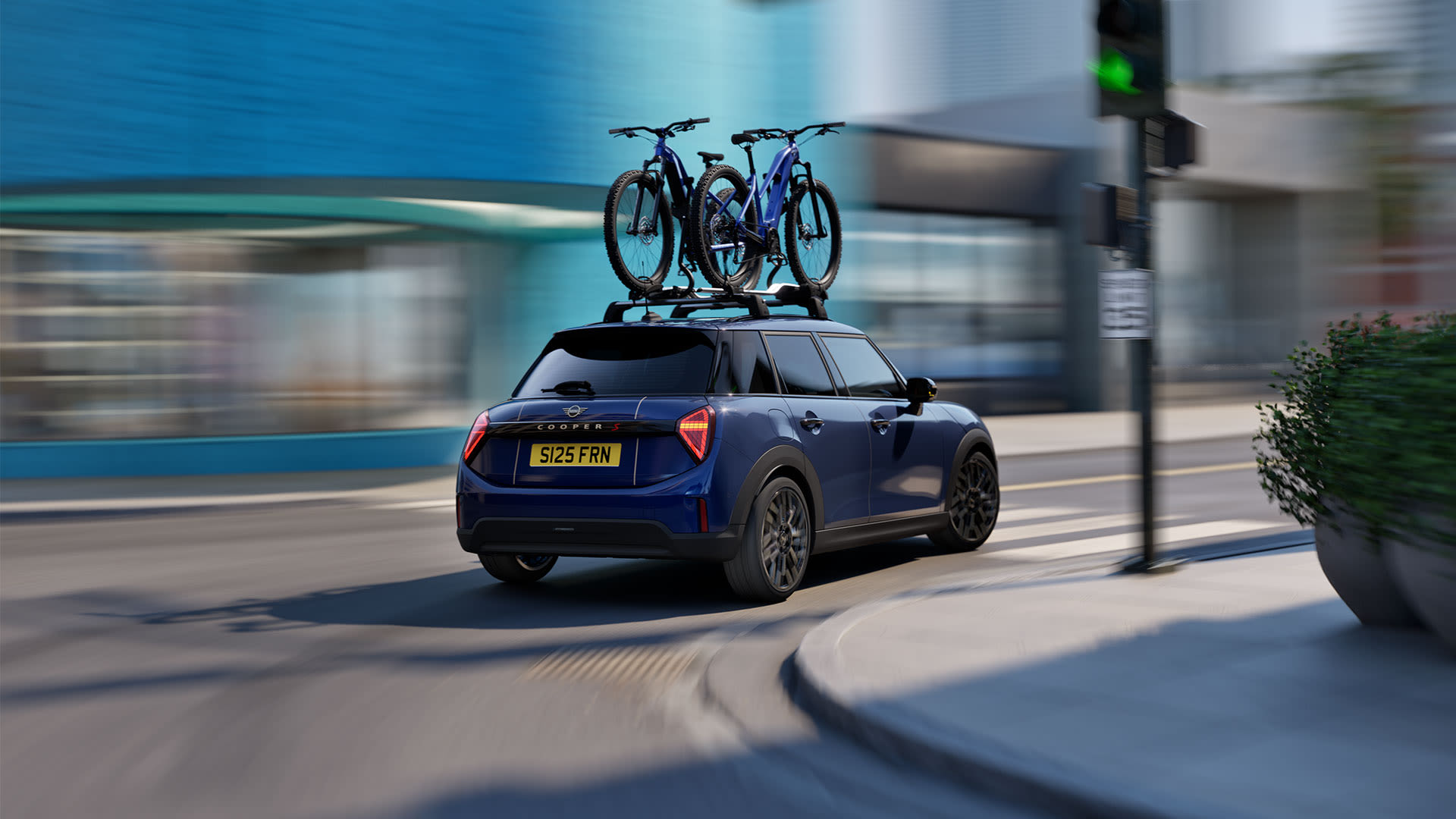 Blue MINI car driving through a city street with two bicycles mounted on the roof.
