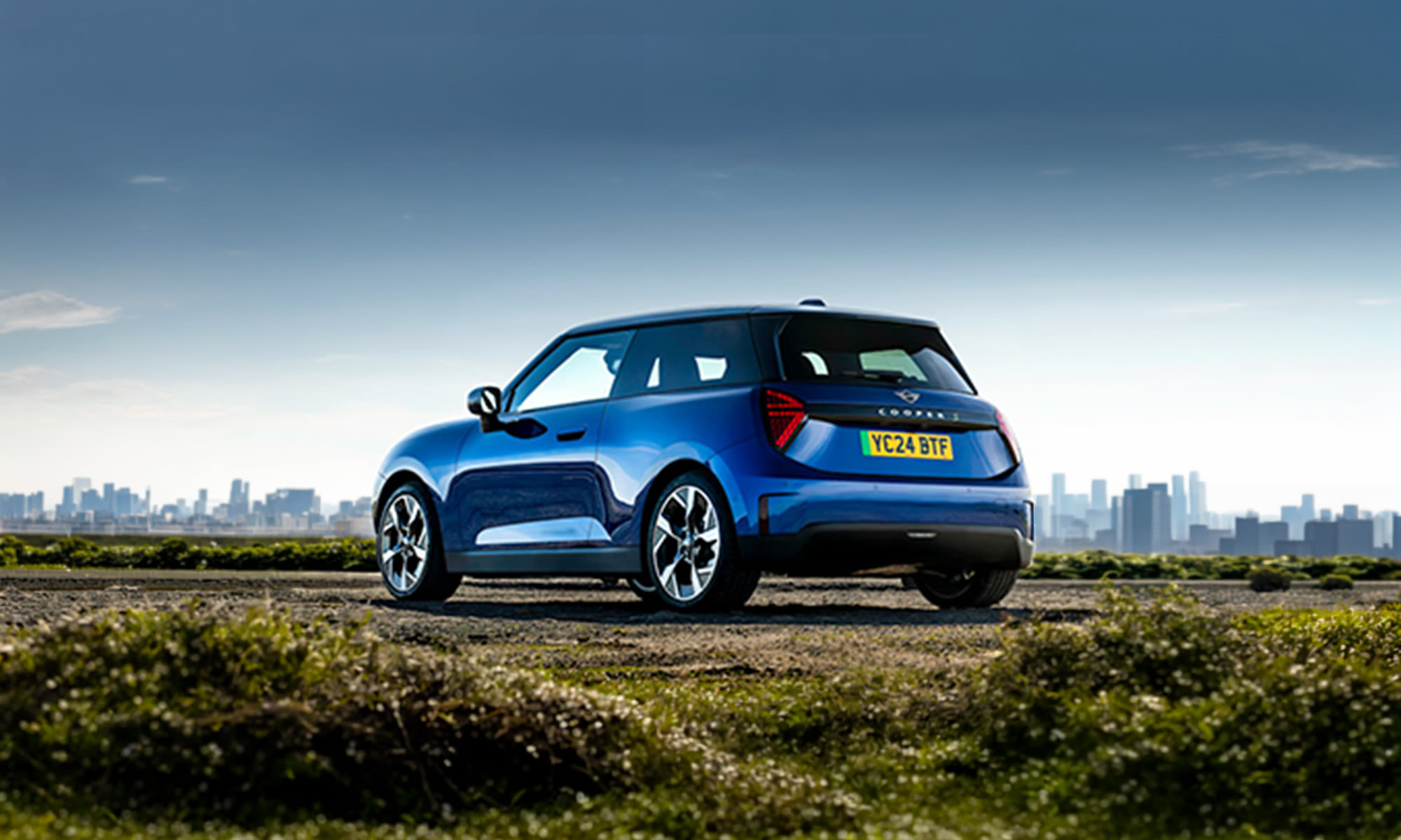 Blue MINI Cooper Electric parked outdoors, viewed from the rear.