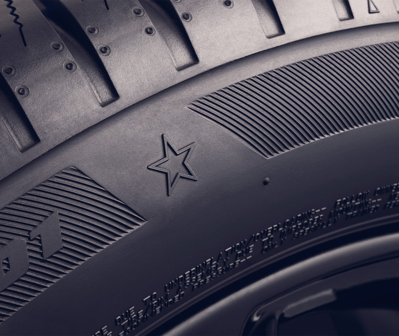 Close-up of a MINI star marked car tire with detailed tread patterns, a star symbol, and textured sidewall design.