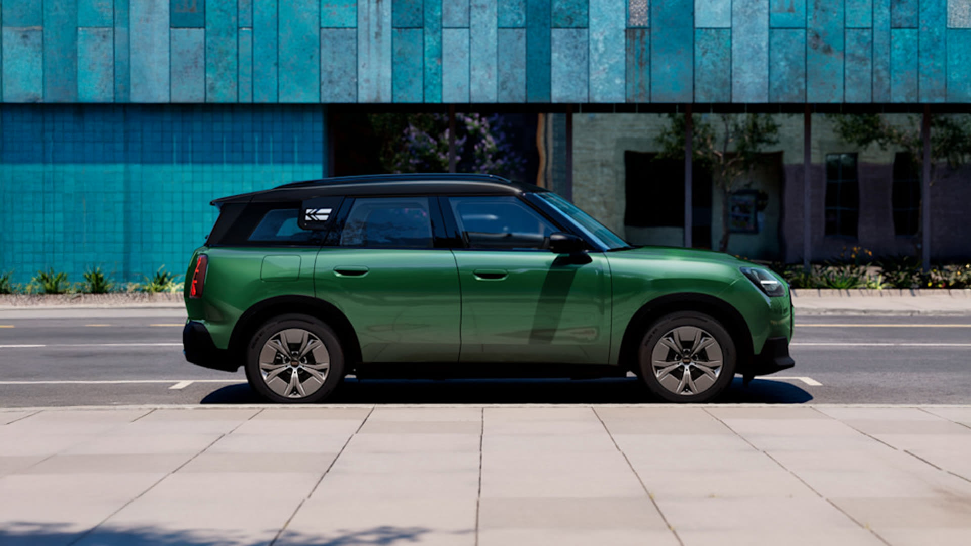 Side view of a green MINI Countryman Electric parked on a city street.