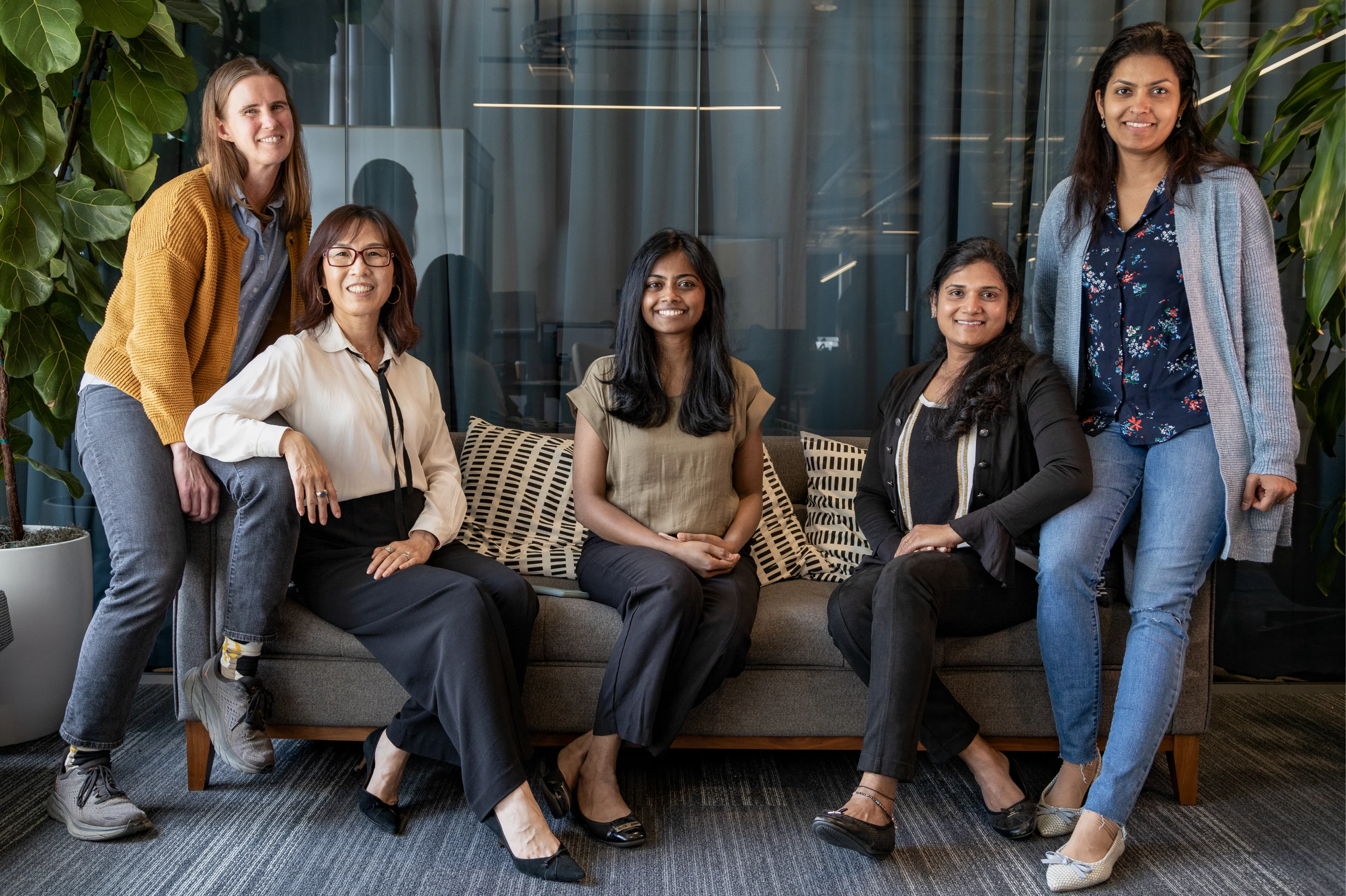 Five women sitting on a couch smiling