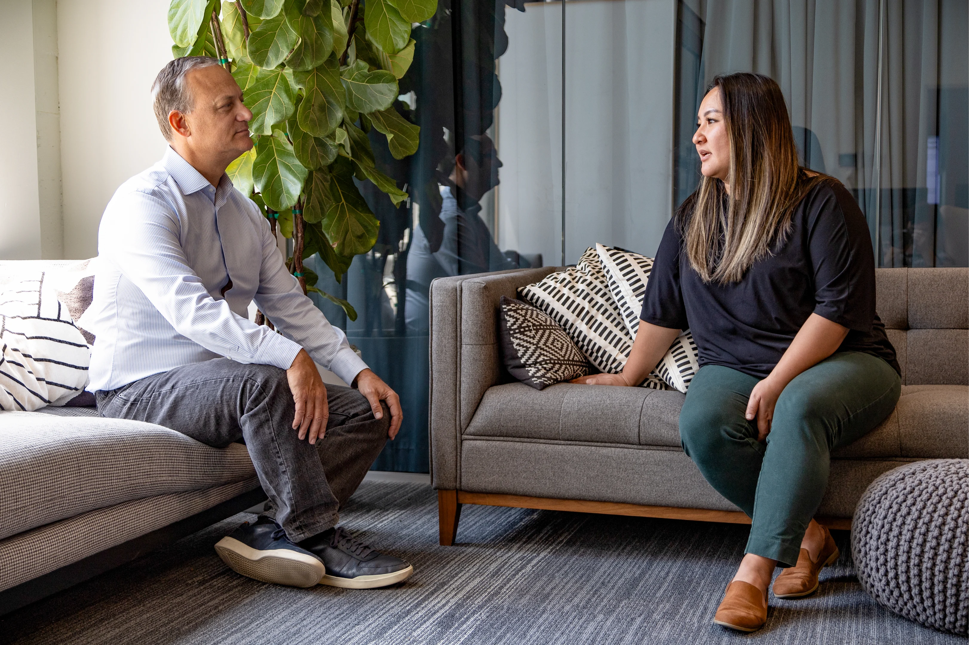 A man and a woman sitting on couches talking.