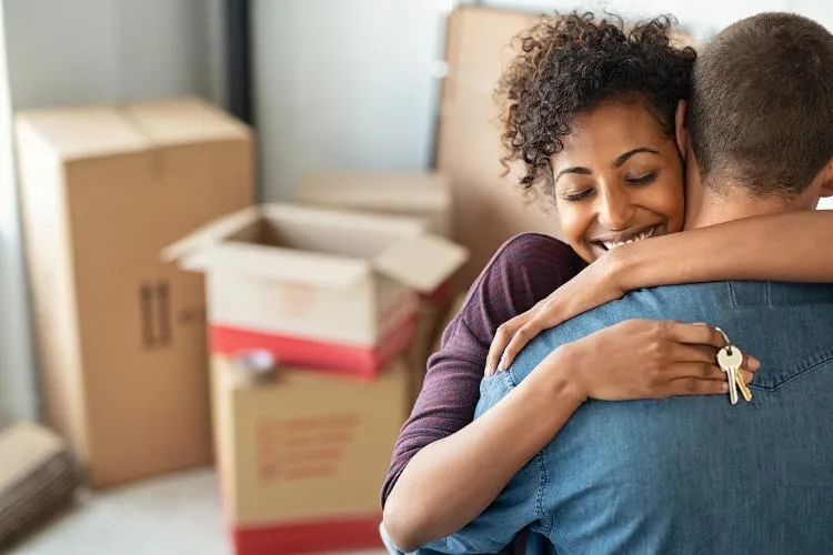 Couple hugging by moving boxes