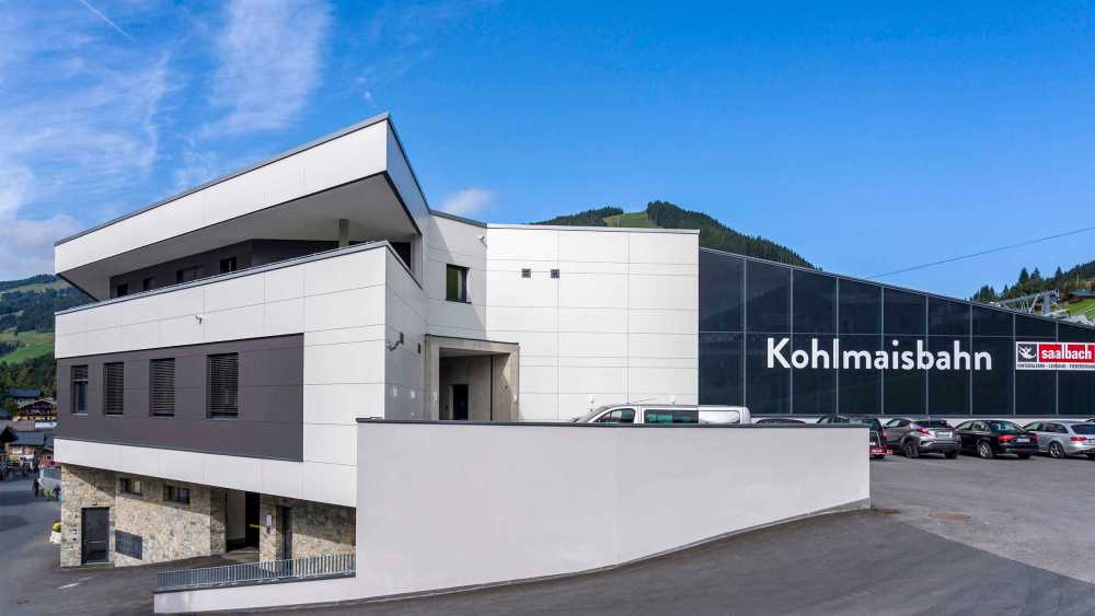 Kohlmaisbahn mit Systemlösungen am Flachdach von BMI Villas und weiß, schwarzer Fassade sowie Parkplatzmöglichkeit neben dem Gebäude