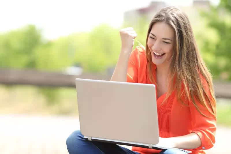 Frau freut sich aufgrund gewisser Anzeigen auf ihrem Laptop
