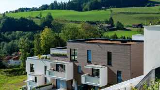 Wohnanlage mit weitläufigen Grünflächen und unterschiedlich hohen Baukörpern und Gründächern 