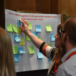 People sticking post it notes on a poster at Shelter Scotland's Annual Homelessness Conference.