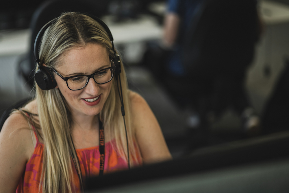 A smiling woman in glasses answers a call from a Shelter supporter
